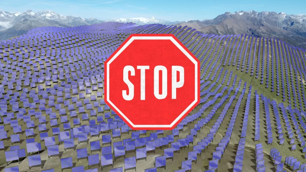 Une image montrant un paysage de montagne recouvert par un immense parc de panneaux solaires bleus, interrompu par un grand panneau stop rouge au premier plan, symbolisant une protestation contre l'implantation de parcs solaires dans des régions naturelles.